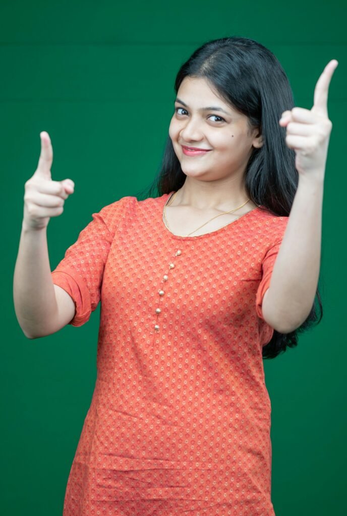a woman giving a thumbs up sign in front of a green background